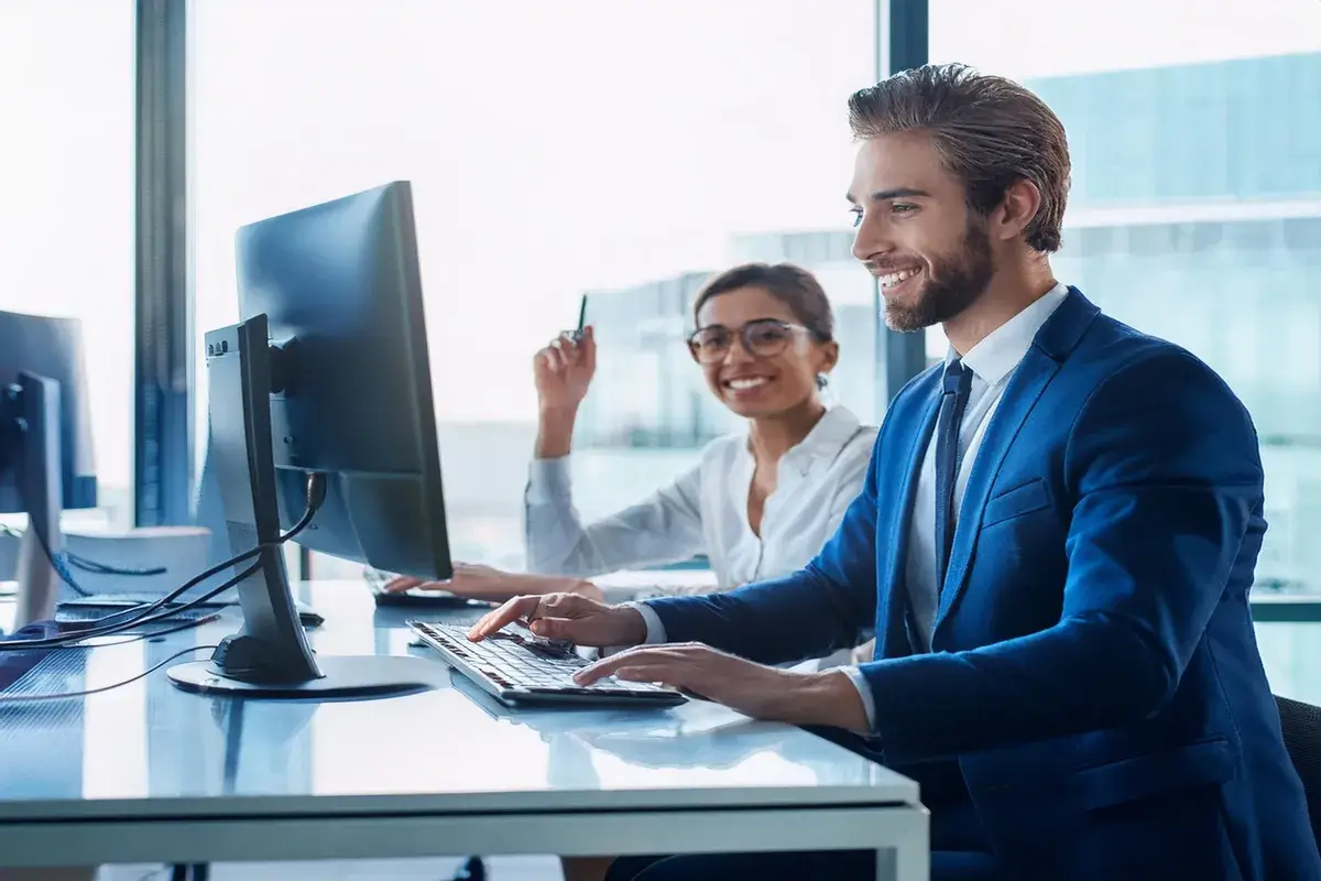 happy IT workers in office clothes looking at computer monitor
