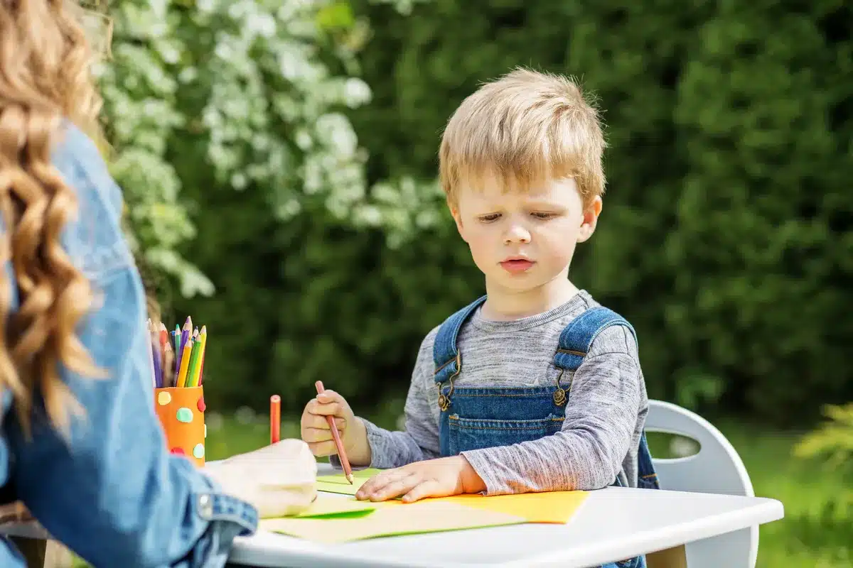 focused-child-drawing-with-babysitter